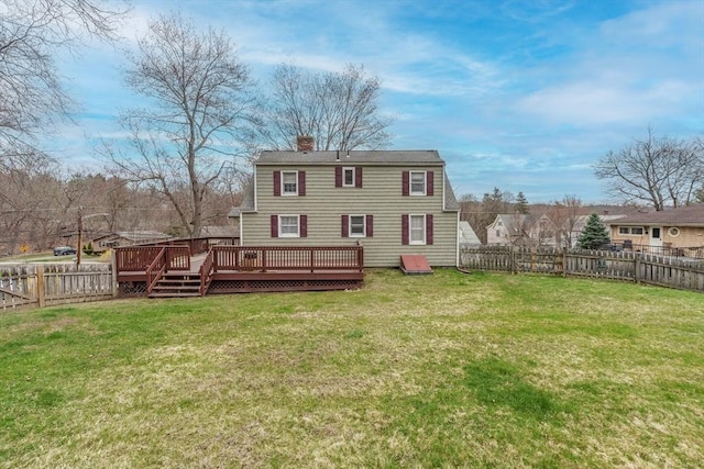 back of property with a lawn, a chimney, a fenced backyard, and a deck