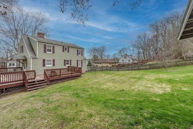 rear view of property featuring a fenced backyard, a chimney, a yard, and a deck