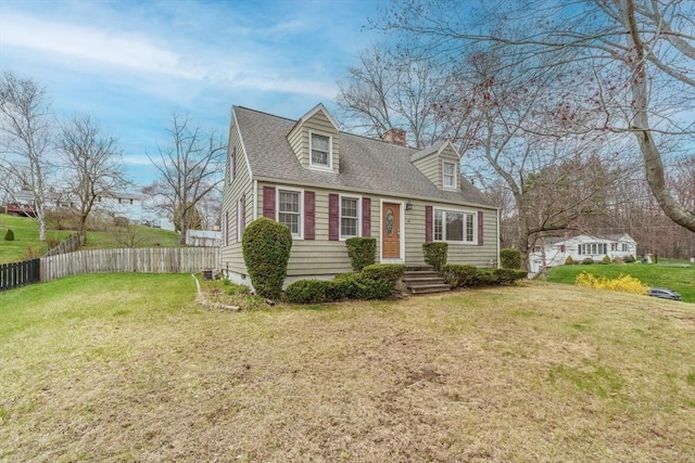 cape cod-style house featuring a chimney, fence, a shingled roof, and a front yard