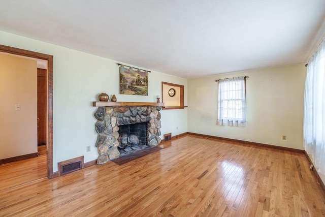 unfurnished living room featuring baseboards, wood finished floors, visible vents, and a fireplace