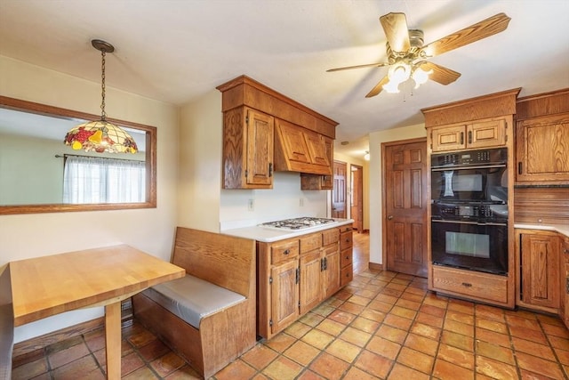 kitchen with dobule oven black, custom exhaust hood, ceiling fan, light countertops, and decorative light fixtures