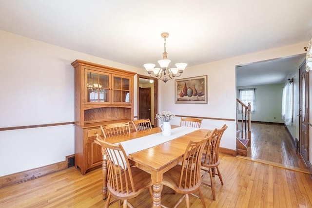 dining space with baseboards, an inviting chandelier, visible vents, and light wood-style flooring