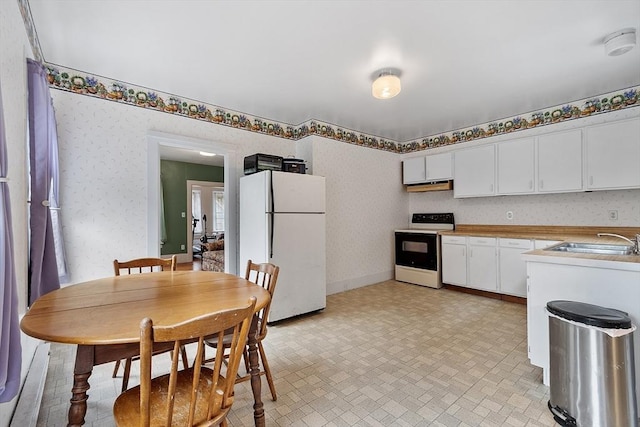 98 Mechanic St, Orange, MA 01364 - kitchen with white appliances, under cabinet range hood, wallpapered walls, white cabinets, and light countertops