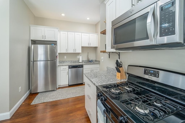 646 E 7th St Unit 1, Boston, MA 02127 - kitchen with stainless steel appliances, white cabinets, dark wood-style flooring, light stone counters, and recessed lighting