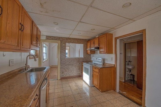 kitchen with sink, dishwasher, electric range, brick wall, and a drop ceiling