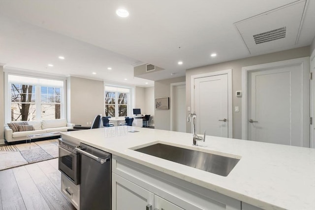 kitchen with dishwasher, recessed lighting, light wood-style floors, and a sink