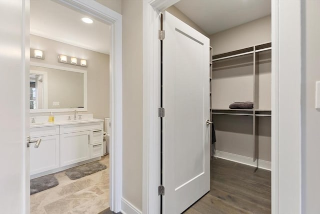 bathroom featuring baseboards, a spacious closet, wood finished floors, and vanity