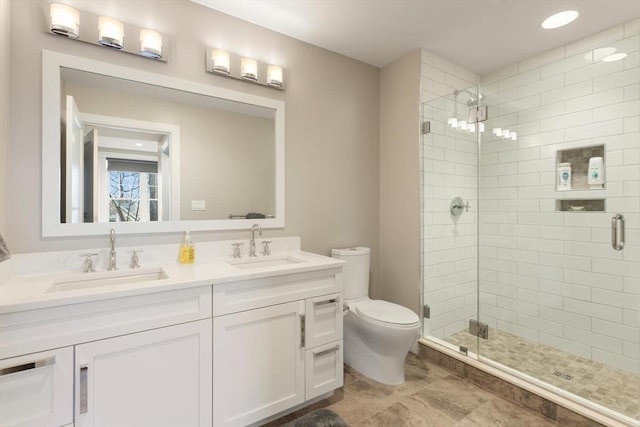 bathroom featuring double vanity, a shower stall, toilet, and a sink