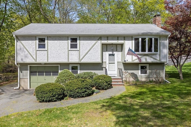 62 Brook St, Wakefield, MA 01880 - raised ranch featuring a chimney, a garage, a front yard, driveway, and stucco siding