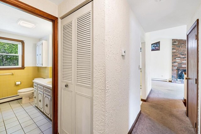 62 Brook St, Wakefield, MA 01880 - corridor with a baseboard radiator, tile walls, light tile patterned floors, and light carpet