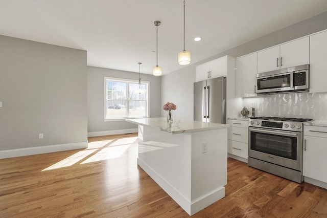 kitchen with backsplash, baseboards, decorative light fixtures, light wood-type flooring, and stainless steel appliances