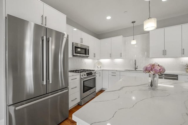 kitchen featuring white cabinets, pendant lighting, stainless steel appliances, and a sink