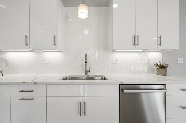 kitchen with light stone countertops, a sink, white cabinets, dishwasher, and backsplash