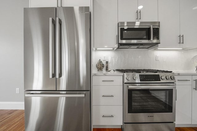 kitchen with light countertops, white cabinets, backsplash, and appliances with stainless steel finishes