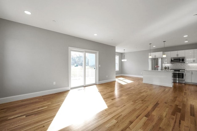 unfurnished living room featuring recessed lighting, baseboards, and light wood-style floors