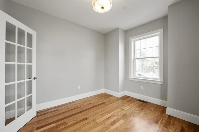 unfurnished room with visible vents, light wood-style floors, and baseboards