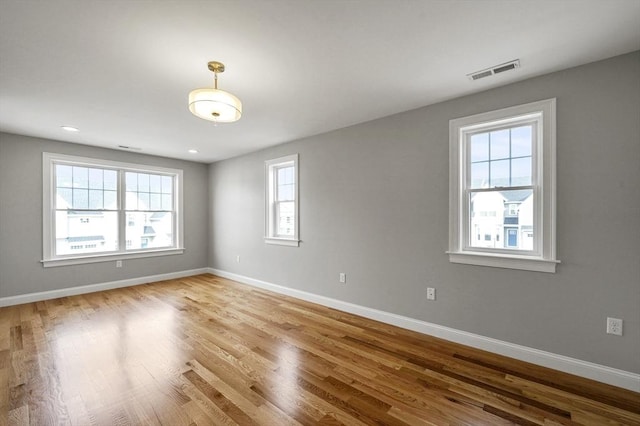 unfurnished room with visible vents, baseboards, and wood finished floors