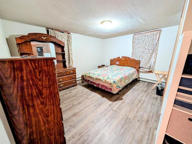 bedroom with wood finished floors, baseboard heating, and a textured ceiling