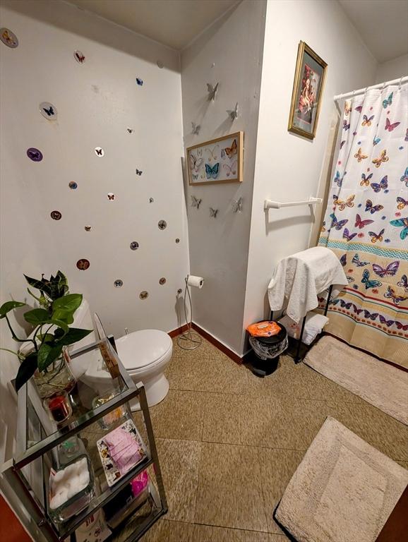 full bathroom featuring baseboards and toilet