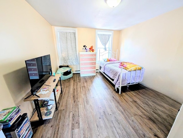 bedroom with a baseboard heating unit, wood finished floors, and baseboard heating