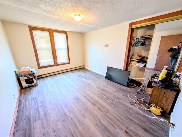 office area with a textured ceiling, wood finished floors, baseboards, and a baseboard radiator