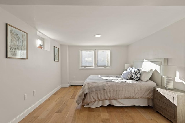 bedroom featuring a baseboard heating unit and light hardwood / wood-style floors