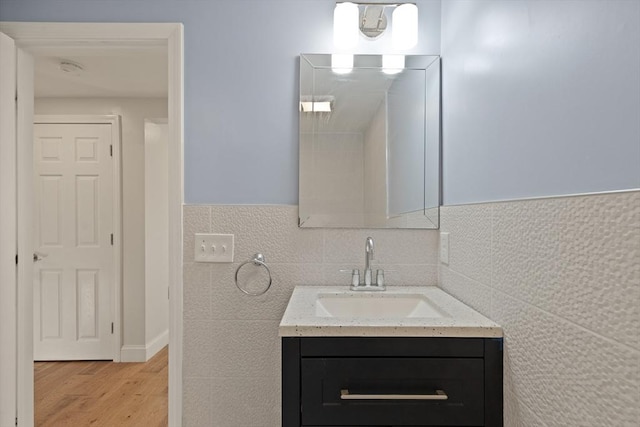 bathroom with tile walls, hardwood / wood-style floors, and vanity