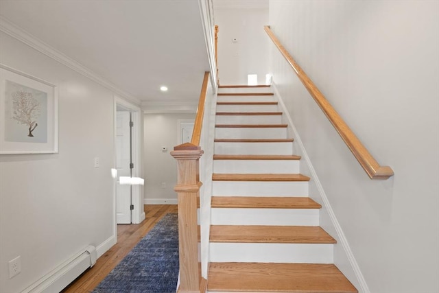 stairway with baseboard heating, ornamental molding, and hardwood / wood-style floors