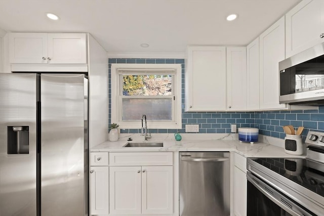 kitchen with sink, light stone countertops, appliances with stainless steel finishes, ornamental molding, and white cabinets