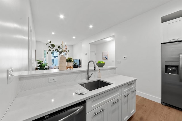 kitchen with light hardwood / wood-style flooring, sink, appliances with stainless steel finishes, and white cabinets