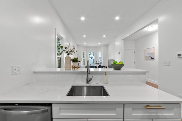 kitchen with light stone counters, sink, and stainless steel dishwasher