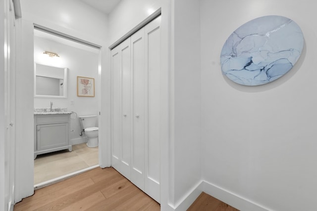 corridor featuring light wood-type flooring and sink