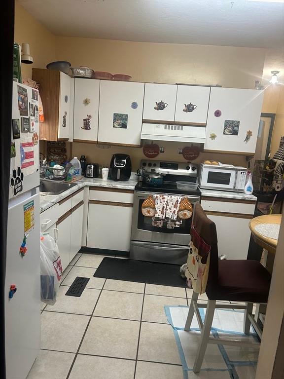 kitchen featuring white cabinetry, white appliances, and light tile patterned flooring