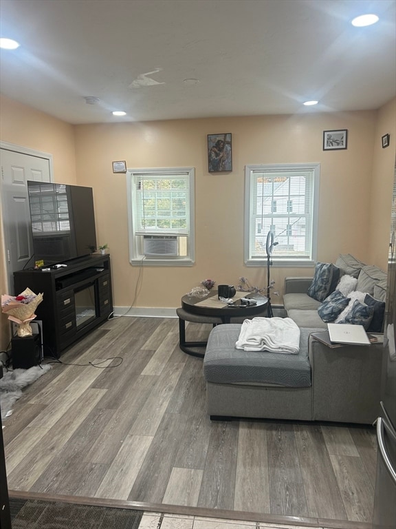 living room with cooling unit, wood-type flooring, and a wealth of natural light