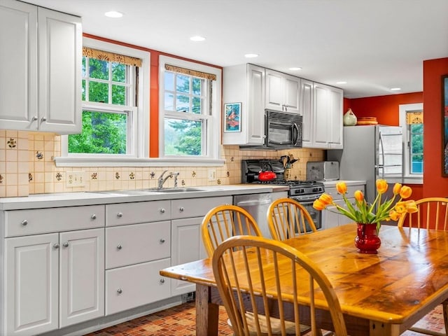 kitchen with stainless steel appliances, brick patterned flooring, light countertops, tasteful backsplash, and recessed lighting