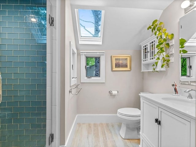 full bathroom with a skylight, vanity, toilet, wood finished floors, and plenty of natural light