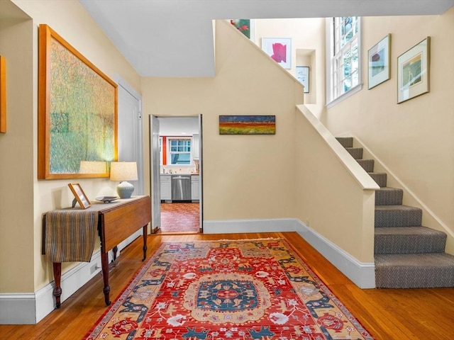 foyer featuring wood finished floors, stairs, and baseboards