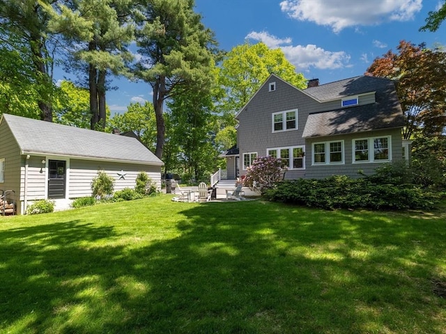 rear view of property with a chimney, a patio, and a yard