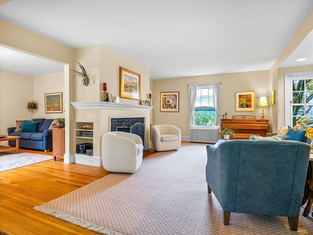 living area with radiator heating unit, wood finished floors, and a fireplace