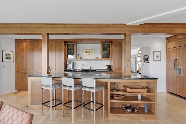 389 River Rd, Carlisle, MA 01741 - kitchen with open shelves, paneled built in fridge, light wood-style flooring, brown cabinets, and a kitchen breakfast bar