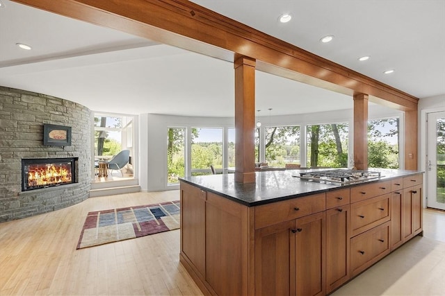 389 River Rd, Carlisle, MA 01741 - kitchen featuring stainless steel gas stovetop, open floor plan, light wood-type flooring, a stone fireplace, and ornate columns