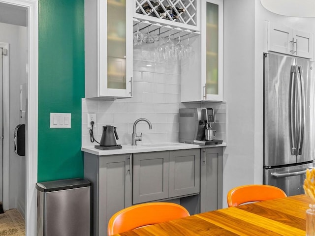 14 Belmont St Unit C, Somerville, MA 02143 - kitchen with freestanding refrigerator, backsplash, gray cabinets, light countertops, and glass insert cabinets