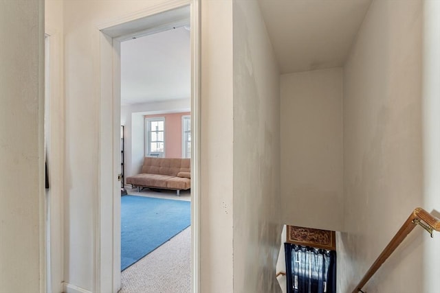 hallway with carpet flooring and an upstairs landing