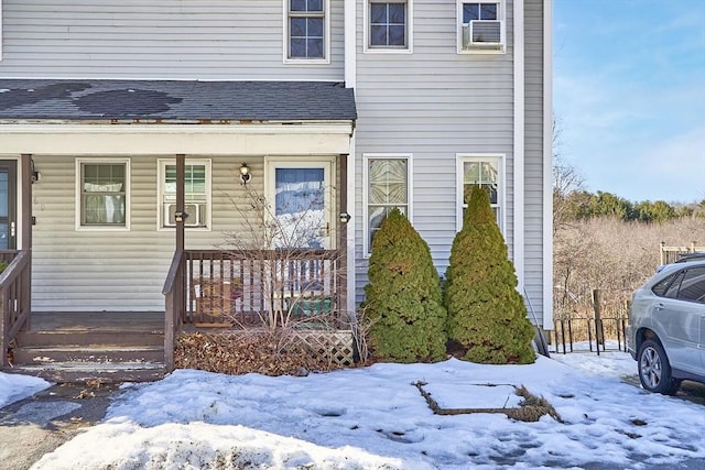 snow covered property entrance with a shingled roof