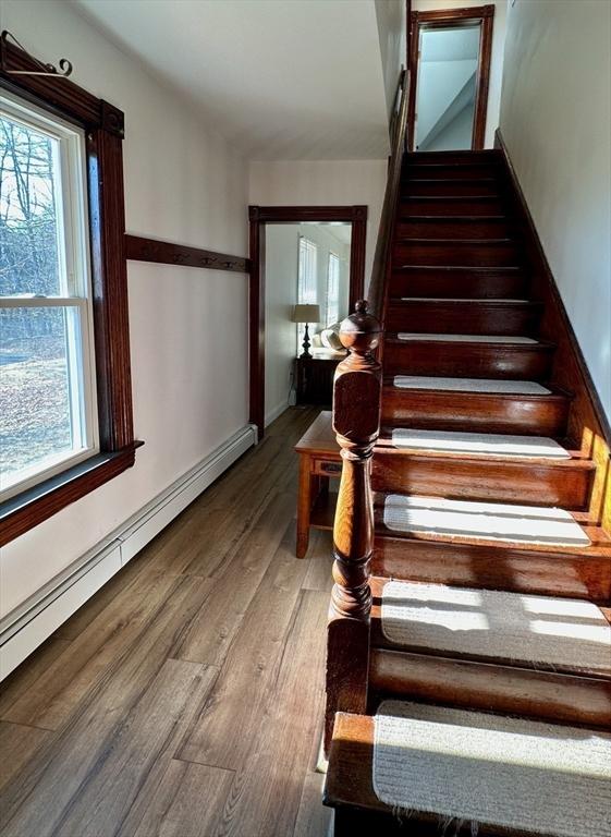 stairs with a baseboard radiator and wood-type flooring