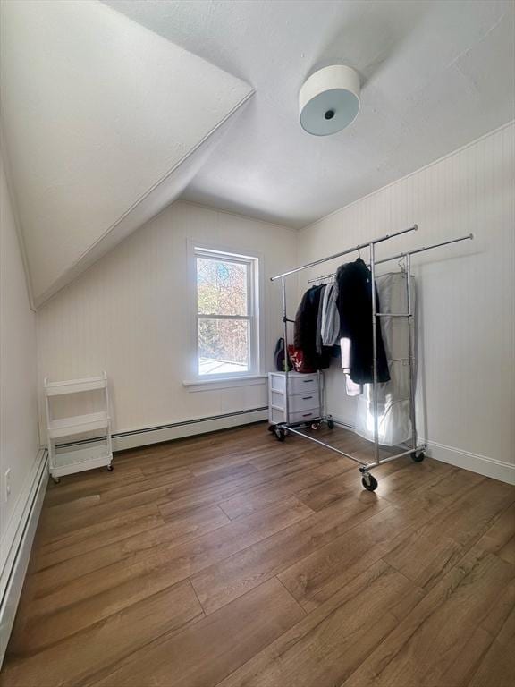 interior space featuring wood-type flooring, vaulted ceiling, and baseboard heating