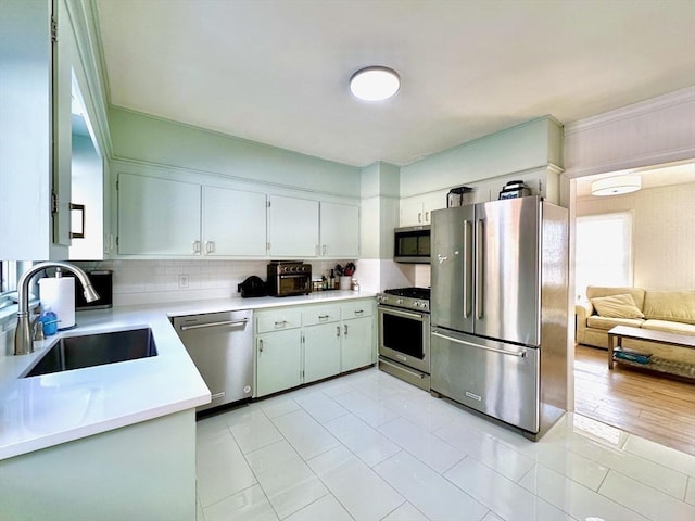 kitchen featuring sink, backsplash, stainless steel appliances, and white cabinets