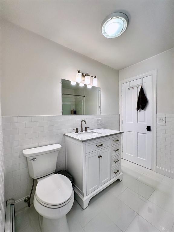 bathroom with vanity, tile walls, tile patterned floors, and toilet