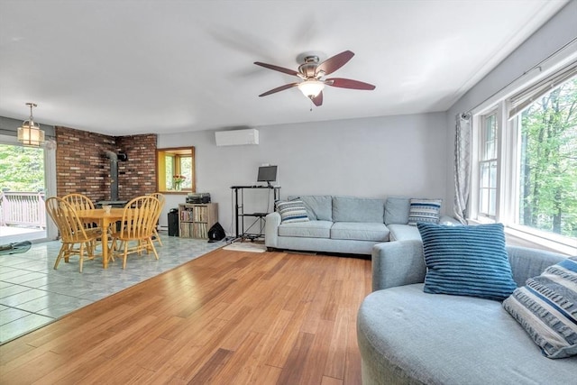 living area with a wall mounted AC, a wood stove, healthy amount of natural light, and a ceiling fan