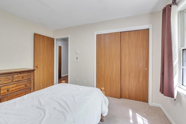 carpeted bedroom with a closet and baseboards
